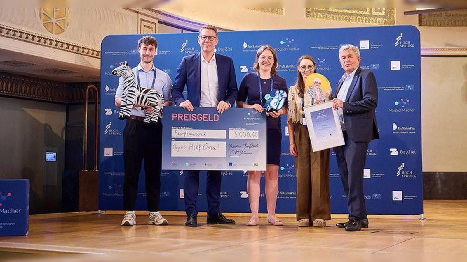 Das Team von „Mission: Hilf Oma!“ bekommt vom Bayerischen Wissenschaftsminister Markus Blume (2. von links) den Preis überreicht.  (Foto: Klaus D. Wolf)