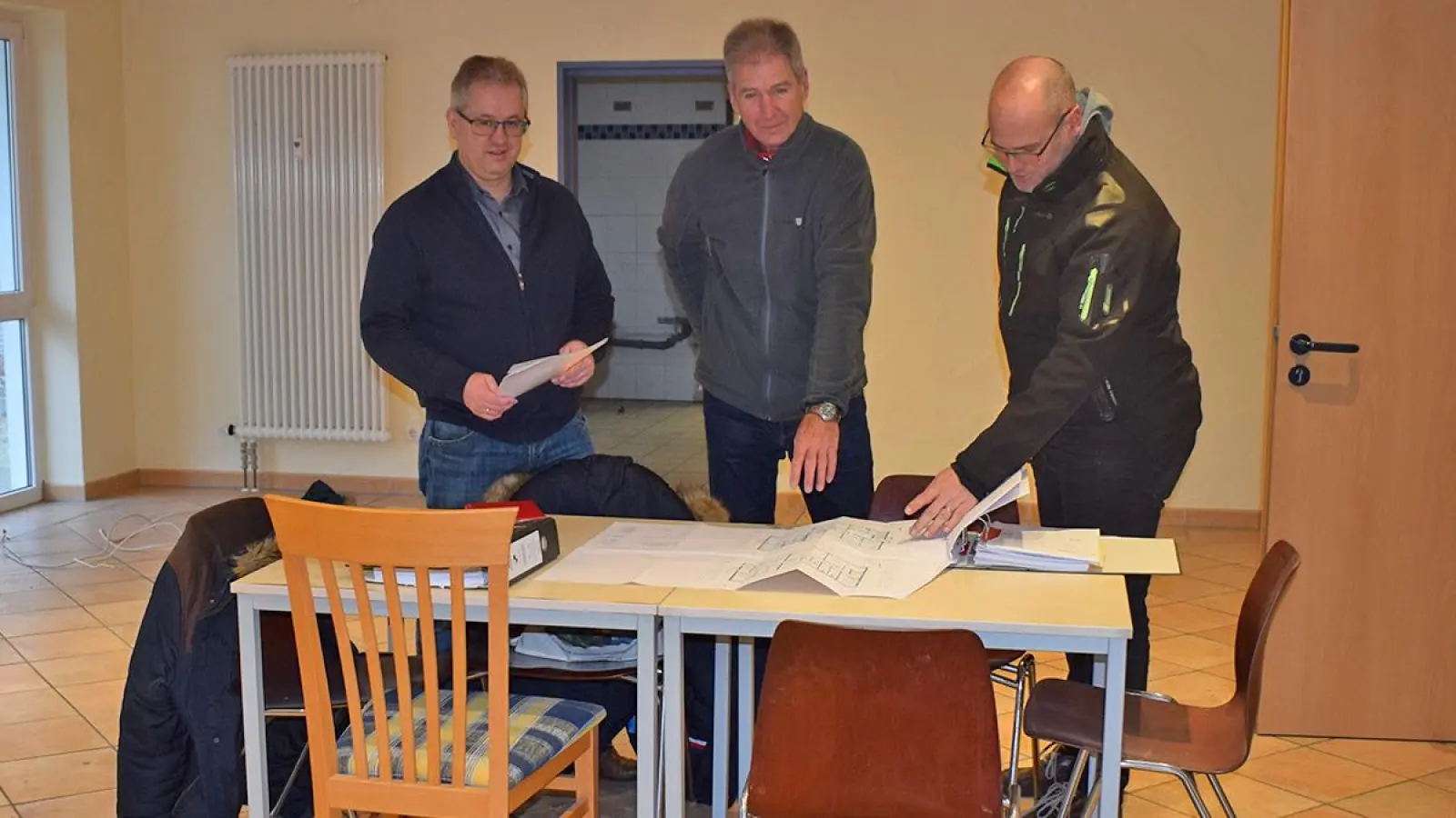 Von links: Bürgermeister Martin Dannhäußer, sein Stellvertreter Raimund Nols, der die Arbeiten Im Gärtlein koordiniert, und Sebastian Popp von der Bauverwaltung studieren in einem der ehemaligen Gasträume, der jetzt zum Gruppenraum für die Krippenkinder wird, die Baupläne. (Foto: Frauke Engelbrecht)