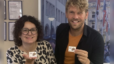 Sandra Baumann, Leiterin der Tourist Information, und Florian André Unterburger, Projektleiter des Jubiläums, präsentieren das neue Souvenir „Festspielhaus in der Streichholzschachtel“. (Foto: Stadt Bayreuth)