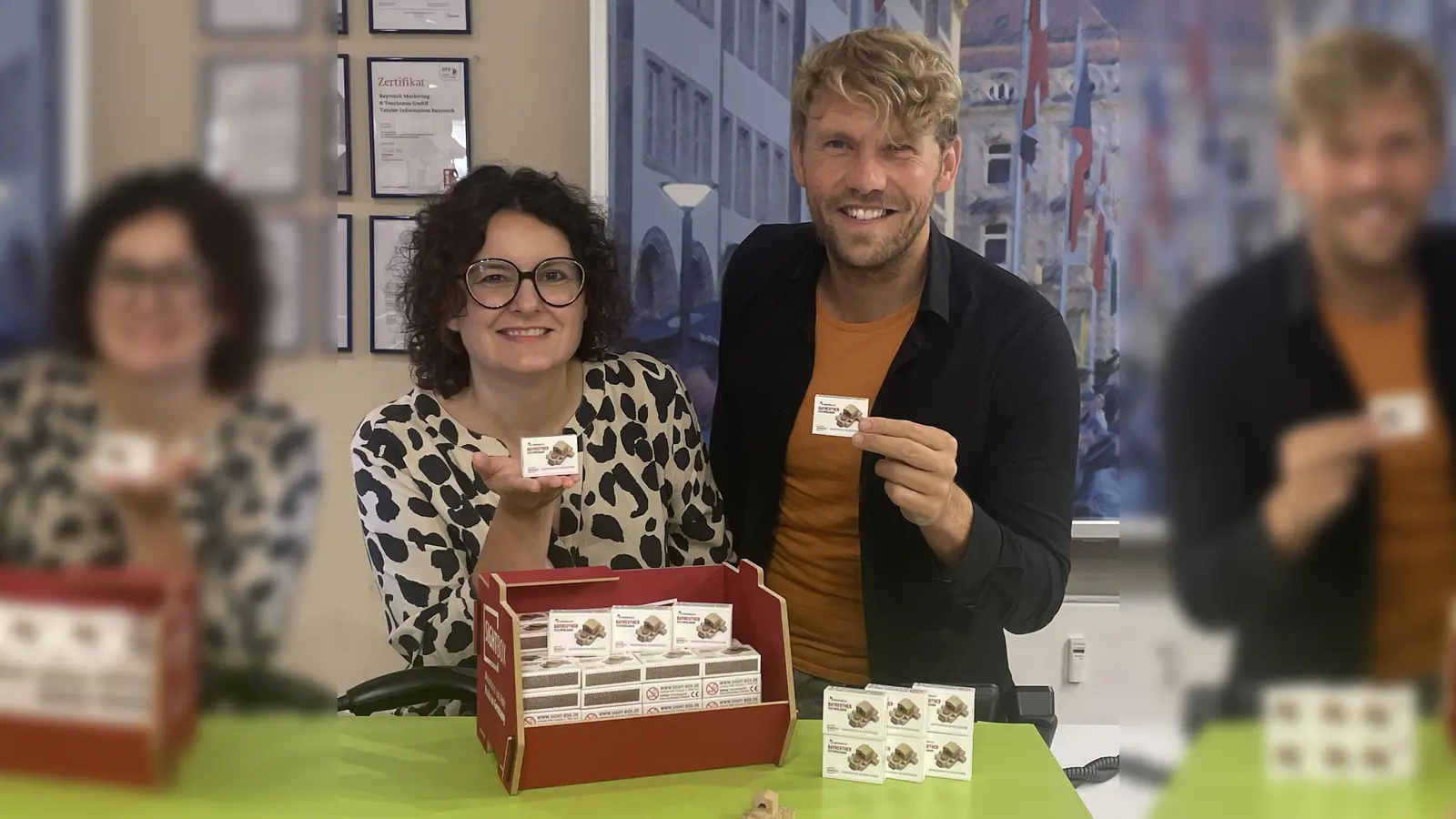 Sandra Baumann, Leiterin der Tourist Information, und Florian André Unterburger, Projektleiter des Jubiläums, präsentieren das neue Souvenir „Festspielhaus in der Streichholzschachtel“. (Foto: Stadt Bayreuth)