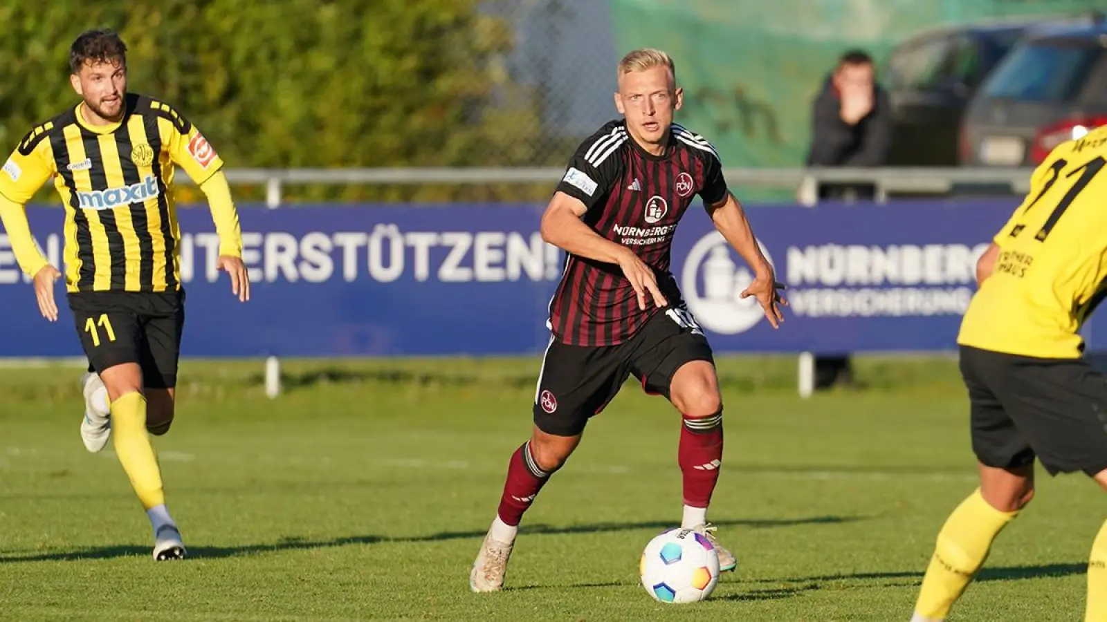 Rot-Schwarz statt Gelb-Schwarz: Benedikt Kirsch im Hinspiel (2:2) am 17. Oktober 2023 am Sportpark Valznerweiher (links: Marco Stefandl, rechts: Tobias Weber). (Foto: 1. FC Nürnberg)