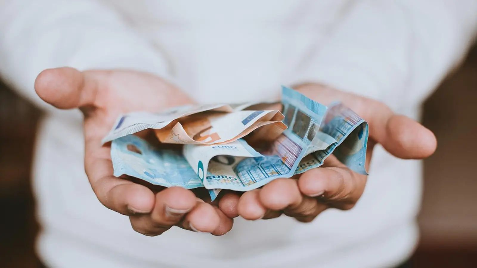 Bargeld in zwei Händen. Bei vielen Kosten muss 2024 in Bayreuth neu gerechnet werden. (Symbolbild: unsplash.com/Christian Dubovan)