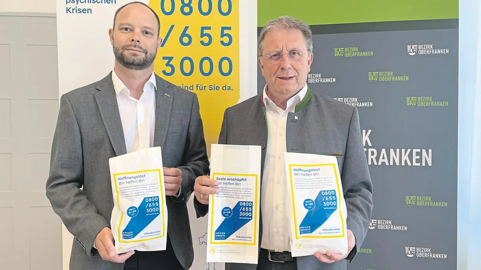 V.l.: Norbert Neumüller, Sozialplaner des Bezirks Oberfranken und Bezirkstagspräsident Henry Schramm mit den bedruckten Bäckertüten. (Foto: red)