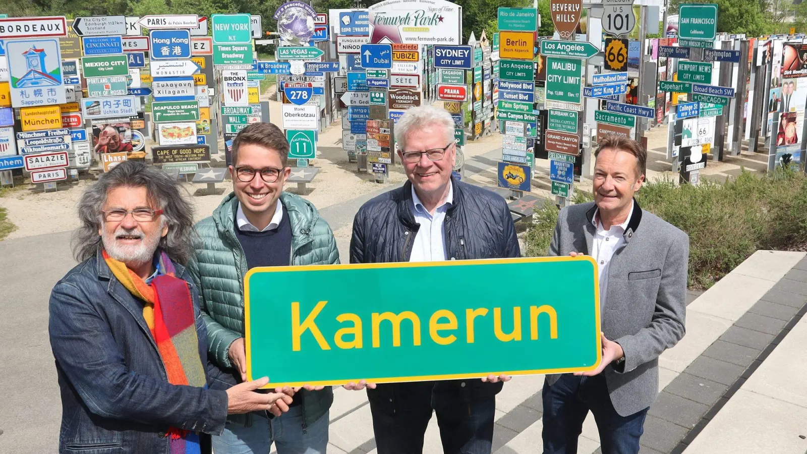 Im Bild: Thomas Ebersberger, Kilian von Chamier von der Bayreuth Marketing &amp;Tourismus GmbH, Stefan Breuer, Erster Bürgermeister der Marktgemeinde Oberkotzau und Klaus Beer, Initiator des Fernweh-Parks, bei der Schildübergabe von „Kamerun“ im Fernweh-Park von Oberkotzau. (Foto: Signsoffame)