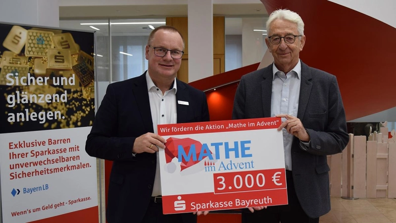 Wolfram Münch, Vorstandsvorsitzender der Sparkasse Bayreuth überreicht den Spendenscheck an den „Mathe im Advent”-Paten Prof. Dr. Peter Baptist. (Foto: Lenkeit)