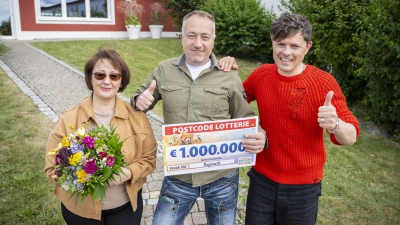 Und plötzlich Millionär: Postcode-Gewinner Oleg freut sich mit seiner Frau und Postcode-Botschafter Michael Patrick Kelly über eine Million Euro.  (Foto: red)