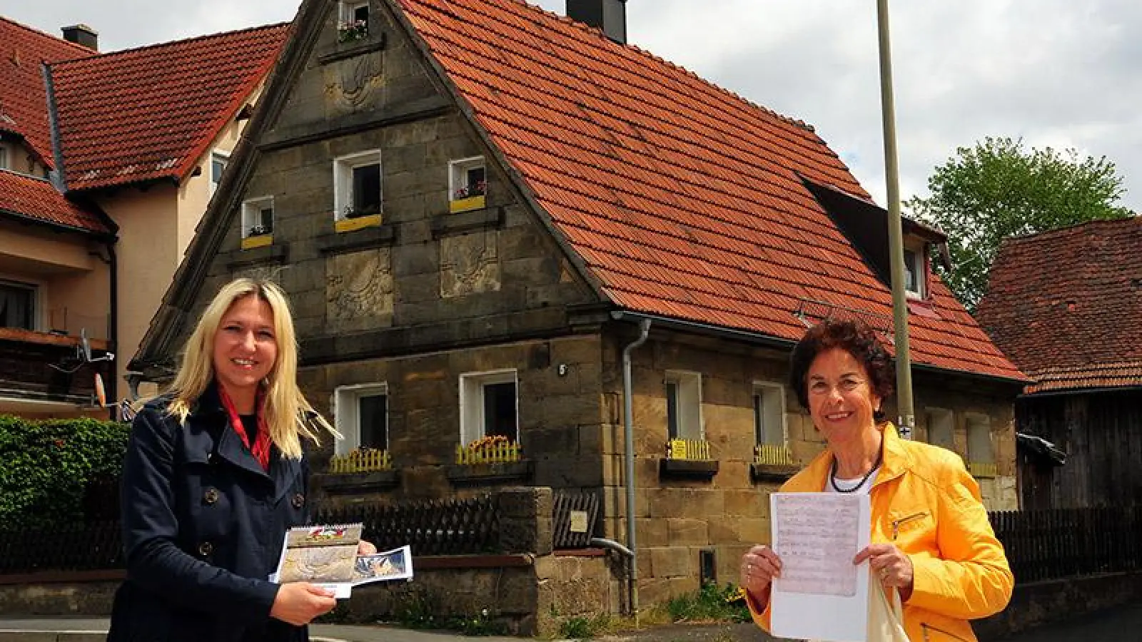 Dr. Silke Launert (links) und die Vorsitzende des Vereins „Rettet die Fachwerk- und Sandsteinhäuser“ Brigitte Trausch vor dem „Fensterschürzenhaus“ in Mistelgau. (Foto: red)