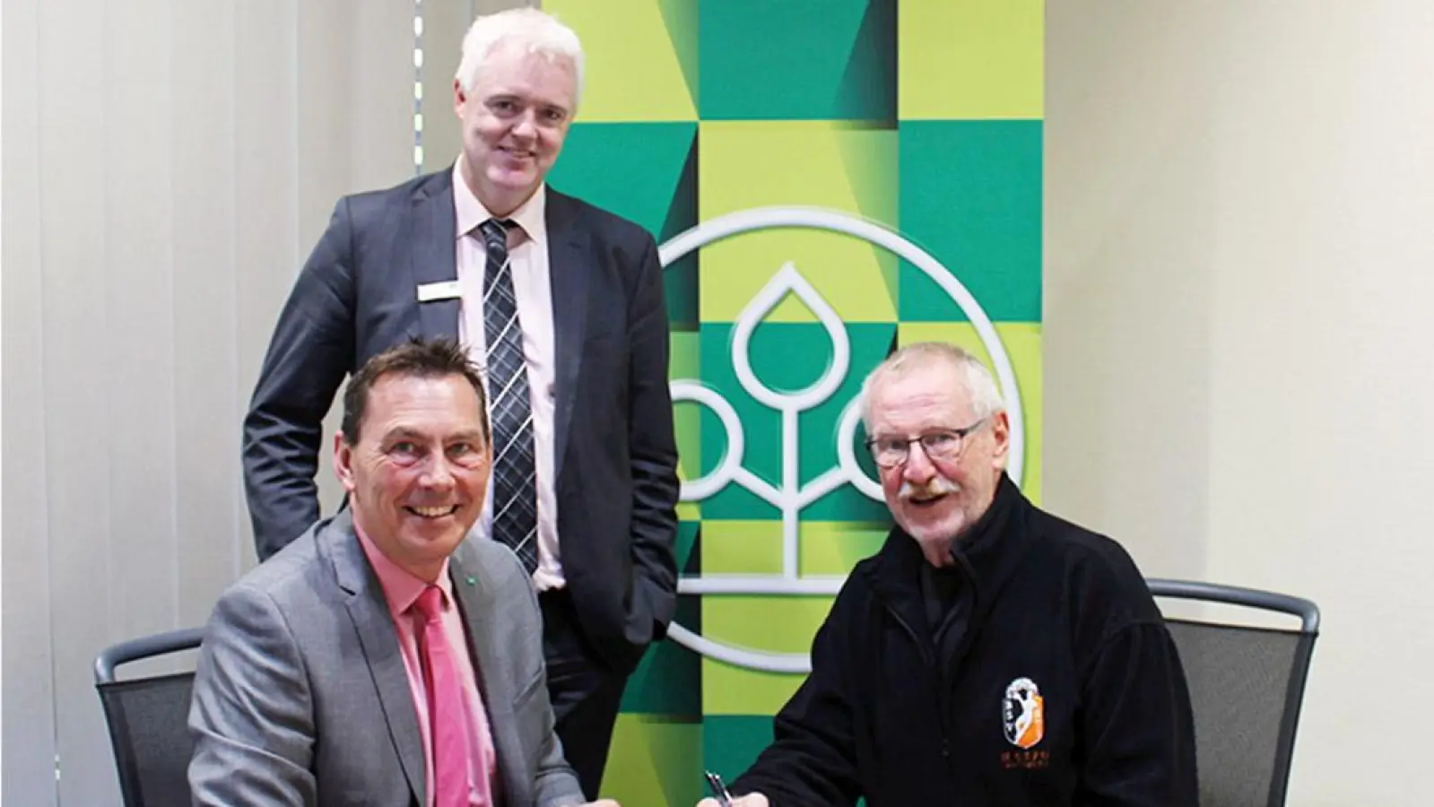 Mit der Vertragsunterzeichnung durch AOK-Direktor Klaus Knorr (l.) und Andreas Berghammer, 1. Vorsitzender des HaSpo Bayreuth (r.), wurde die Zusammenarbeit besiegelt. AOK-Fach-<br>bereichsleiter Marko Ahrens (stehend) war für die inhaltliche Ausgestaltung der Vereinbarung verantwortlich. (Foto: AOK)