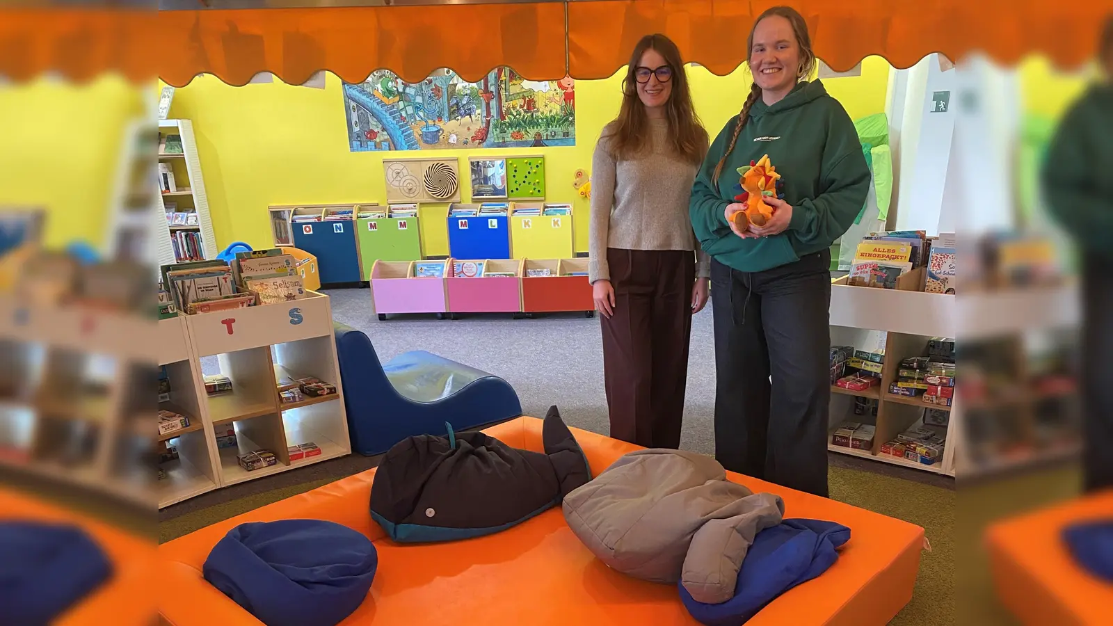Kathrin Weishäupl (li.) von Miss Smarthead GmbH übergibt das Kuschelnest an Kinderbibliotheksleitung Alexandra Warzecha. (Foto: RW21 Stadtbibliothek)