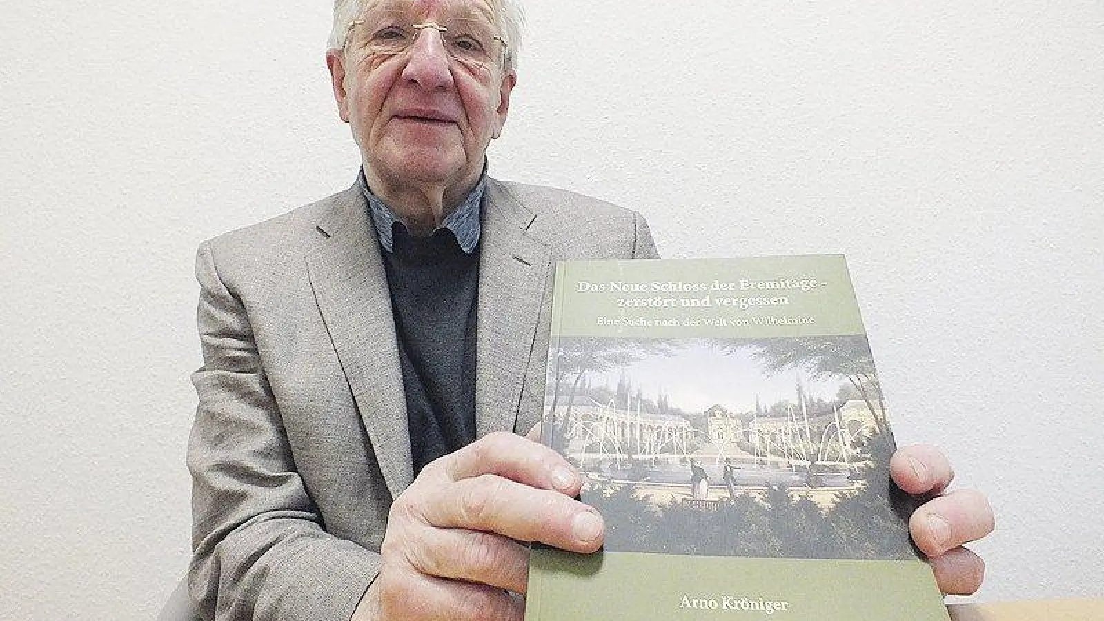 Dr. Arno Kröniger mit seinem Buch über das Neue Schloss in der Eremitage vor der Zerstörung am Ende des Zweiten Weltkriegs, Foto: Roland Schmidt (Foto: inBayreuth.de)