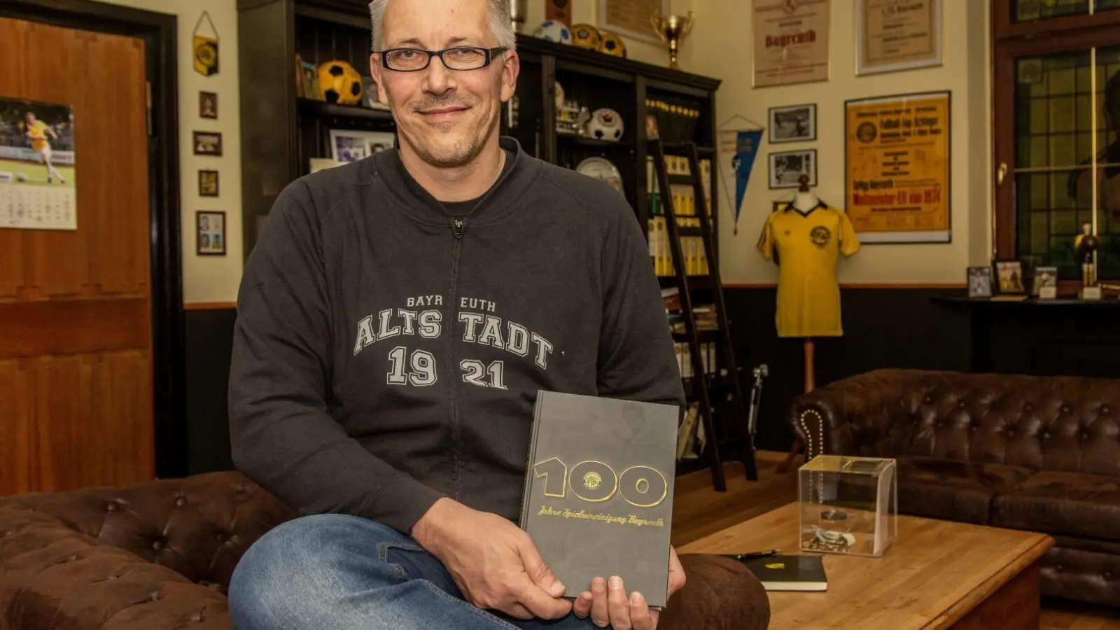Uwe Glaser, Geschäftsführer des Tribünenkults, der das Jubiläumsbuch herausgeben will mit einem Musterbuch in seine Händen. (Foto: inBayreuth.de)