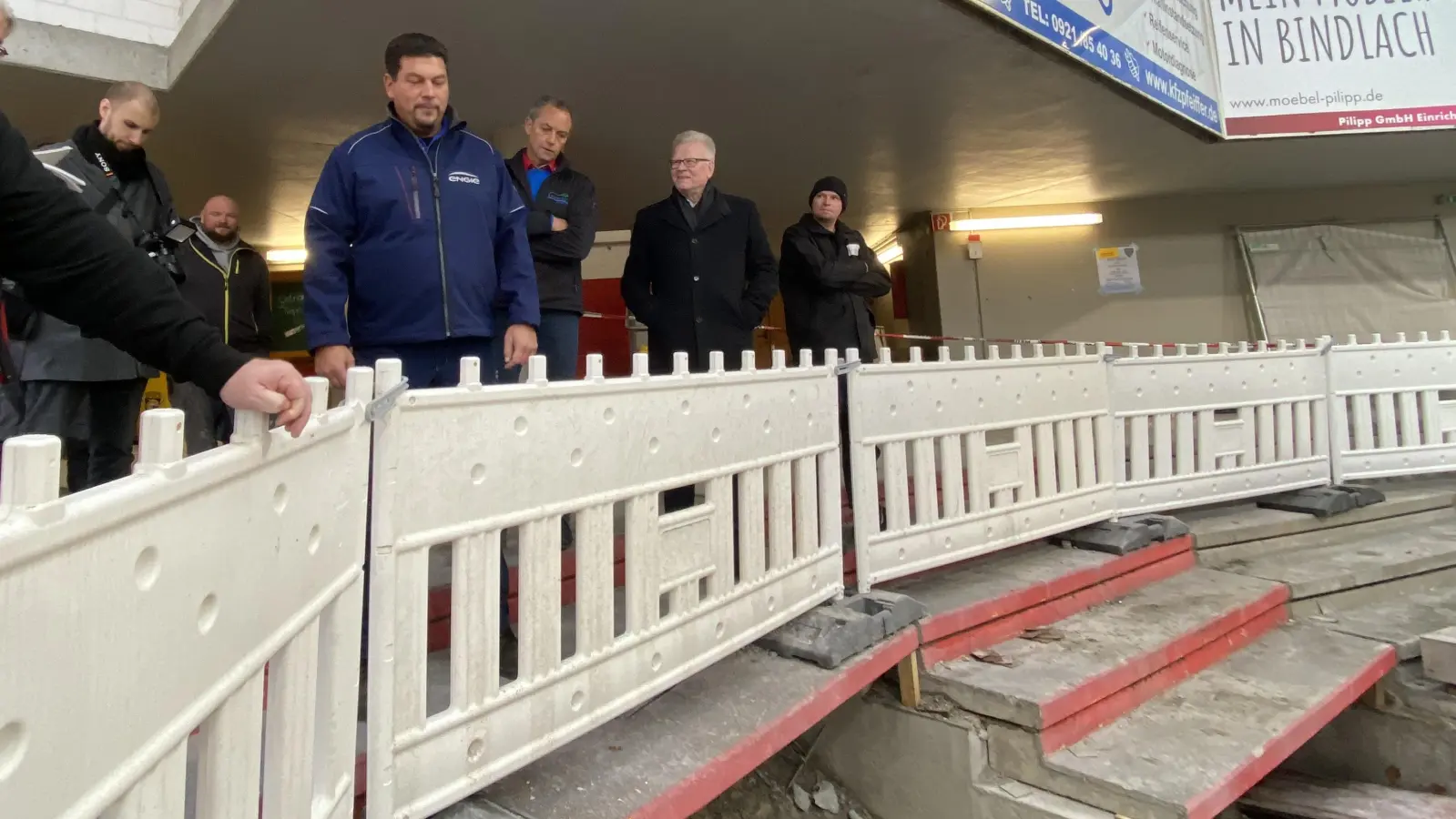 Im Bereich der Mainkurve werden im Zuschauerbereich Rohre ausgetauscht. Von links: Techniker Heiko Zeitler (Firma Engie), Sportamtsleiter Christian Möckel und Oberbürgermeister Thomas Ebersberger im Eisstadion. (Foto: Lenkeit)