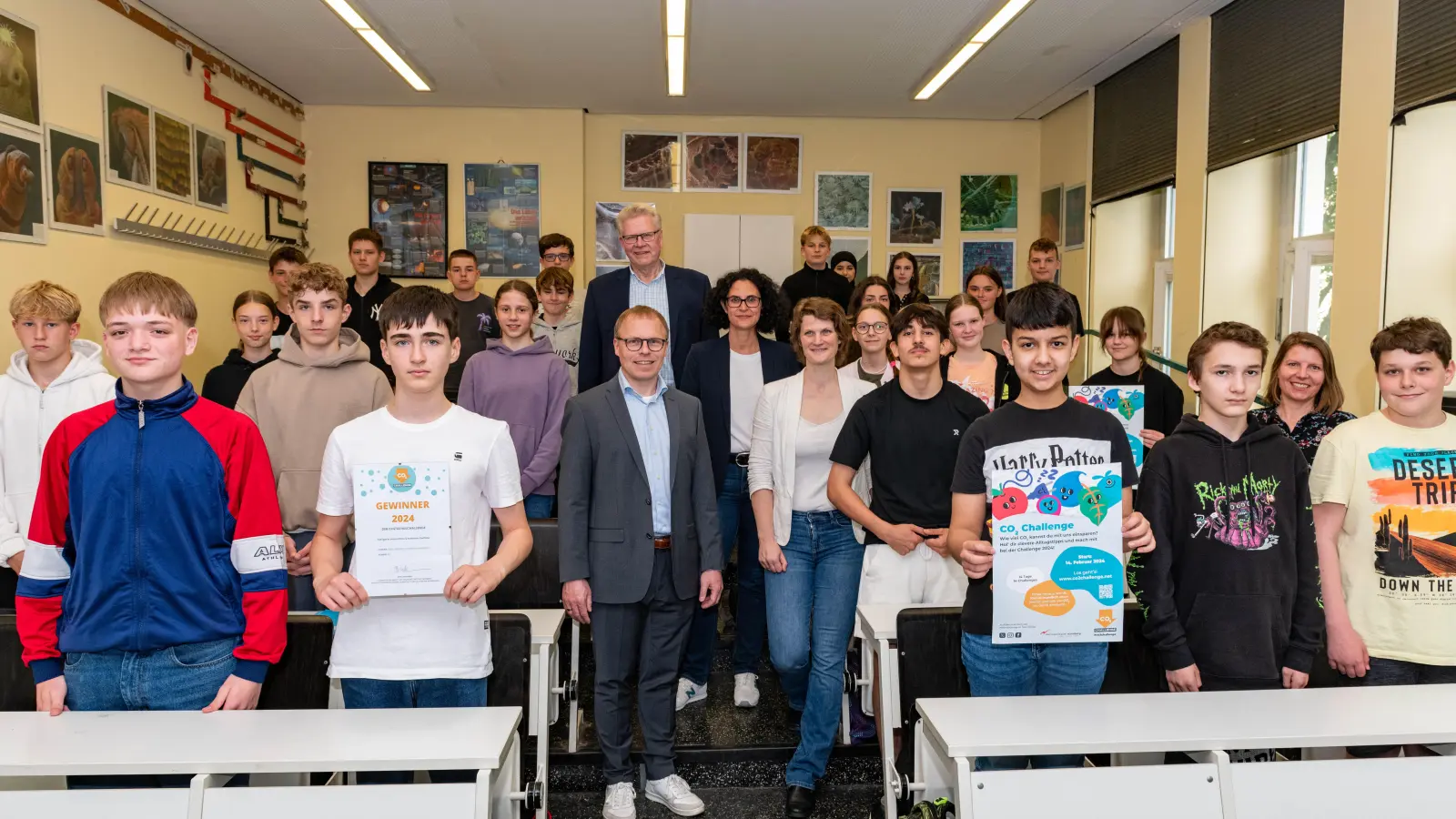 Schülerinnen und Schüler der 8c des Graf-Münster-Gymnasiums und ihre Lehrerin Tabea Tchokothe (2. Reihe re.) lassen sich für ihren Gewinn der CO2-Schulchallenge der Europäischen Metropolregion Nürnberg in der Kategorie „Kreativstes und innovativstes Portfolio“ feiern. Es gratulierten (im Mittelgang von hinten): Oberbürgermeister Thomas Ebersberger, Schulpflegerin Luisa Barjak-Funke, Klimaschutzmanagerin Gesa Thomas und Schuldirektor Christian Kramer.<br> (Foto: Lauri Redel, Graf-Münster-Gymnasium)