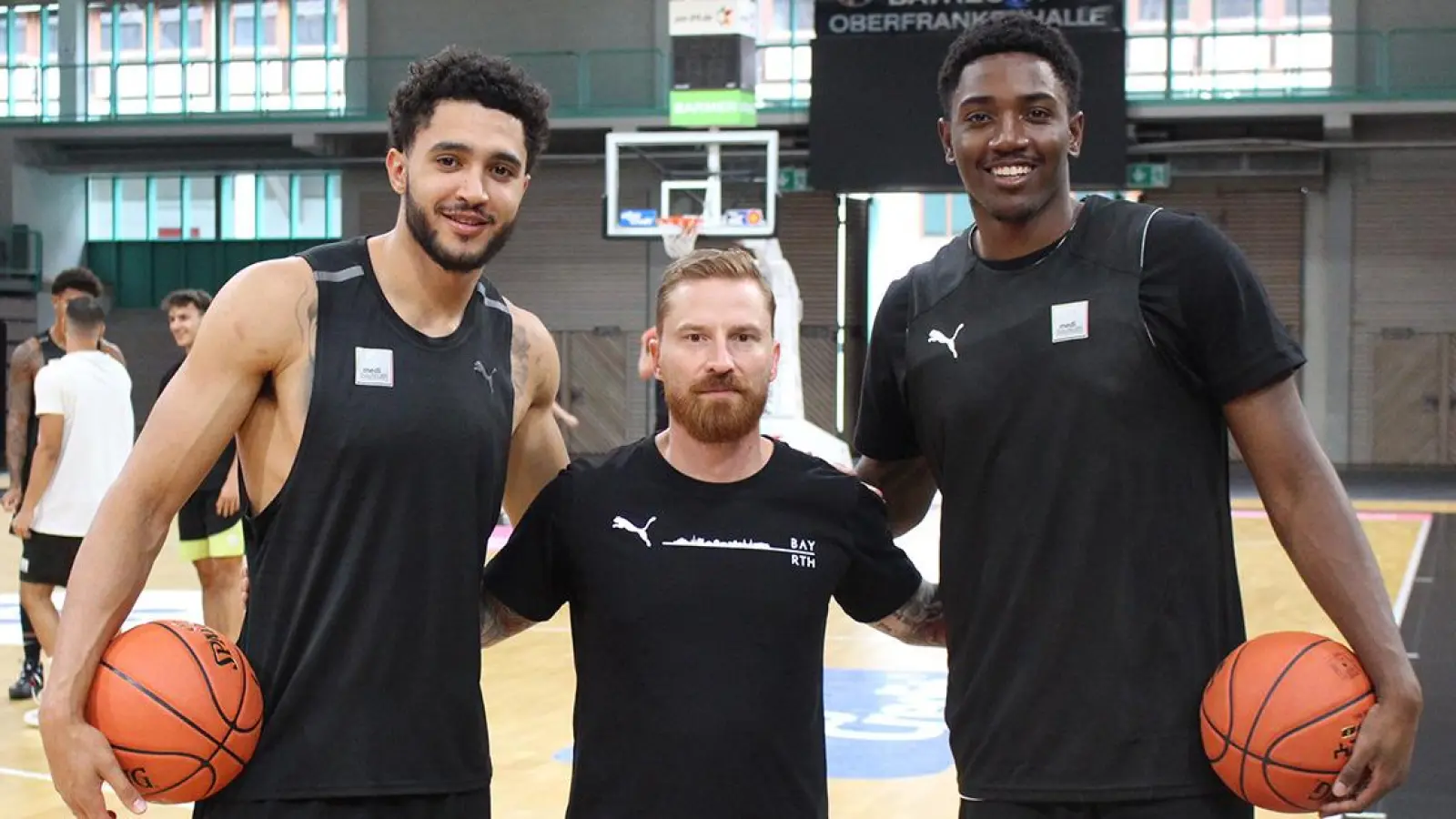 Die kanadischen Neuzugänge Jackson Rowe (links) und Kalif Young (rechts) mit Coach Lars Masell beim Trainingsauftakt. (Foto: medi Bayreuth)