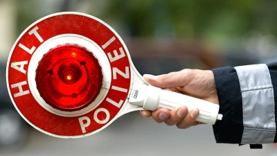 Verkehrskontrolle mit roter Polizeikelle. (Symbolbild: Adobe Stock)
