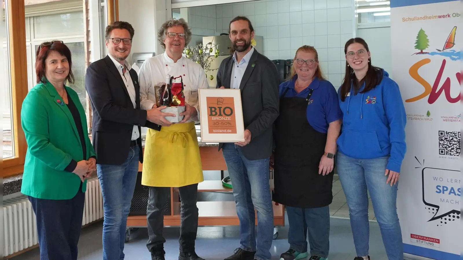 Siegelübergabe im Schullandheim Pottenstein. V.l.n.r.: Sandra Böhner, Geschäftsführerin des Schullandheimwerk Oberfranken e.V., Landesvorsitzender Bioland Bayern Thomas Lang, Koch Wolfgang Kress, Josef Schmidt vom Bioland-Vorstand Bayern, Köchin Angelika Müller und Bereichsverantwortliche der Hauswirtschaft Christin Schick. (Foto: Nina Burgrainer)
